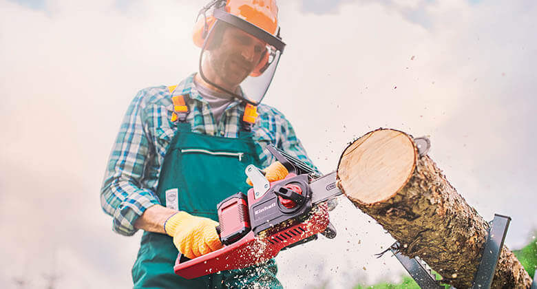 Person cutting tree trunk with chainsaw