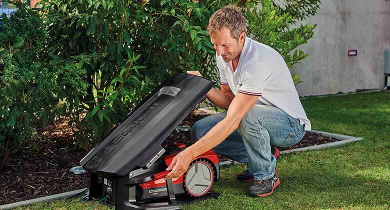 man with a robotic lawn mower in a robot lawn mower garage