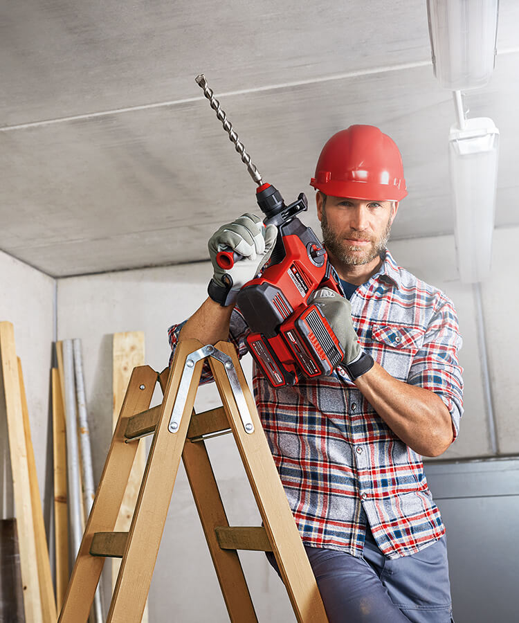 A man works on a construction site with a rotary hammer